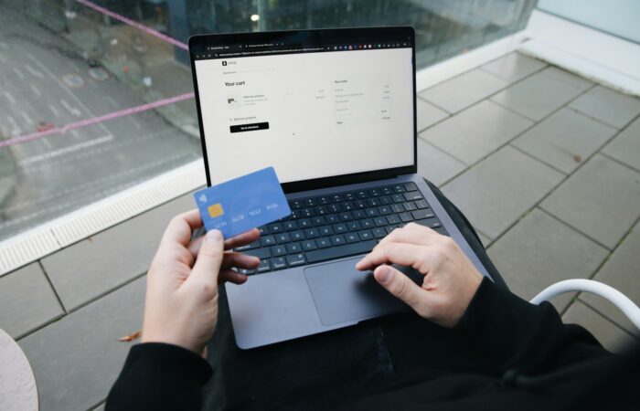A person sitting in a chair with a laptop and a credit card